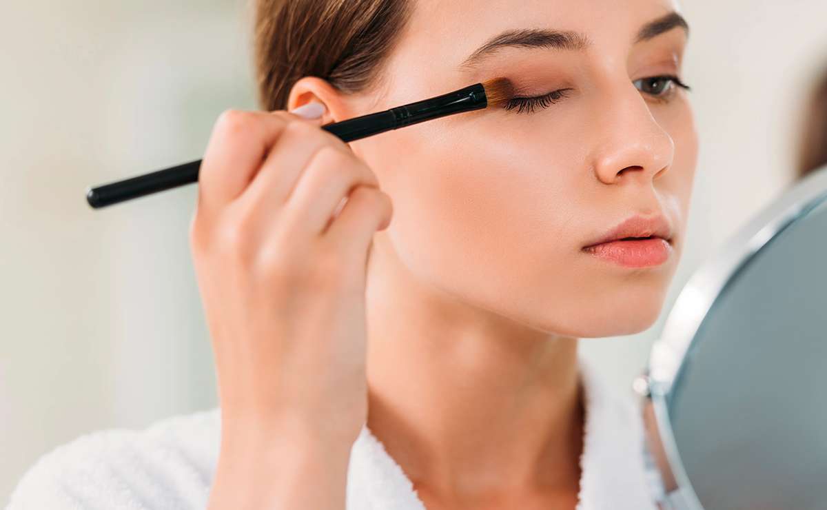 Donna che applica ombretto nude sulla palpebra per un trucco occhi naturale e veloce con pennello da sfumatura