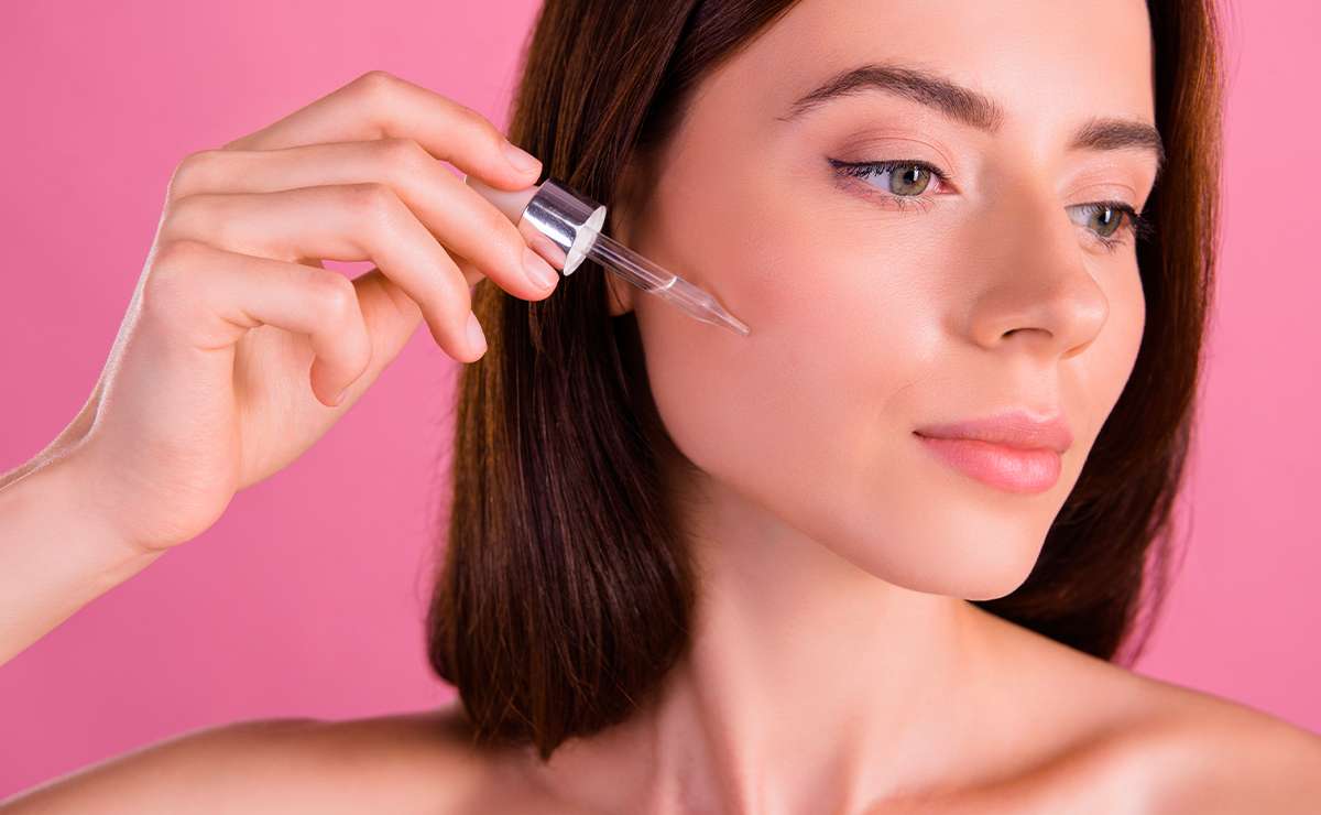 Giovane donna applica un siero viso con contagocce per preparare la pelle al trucco naturale, step fondamentale del nude make-up moderno