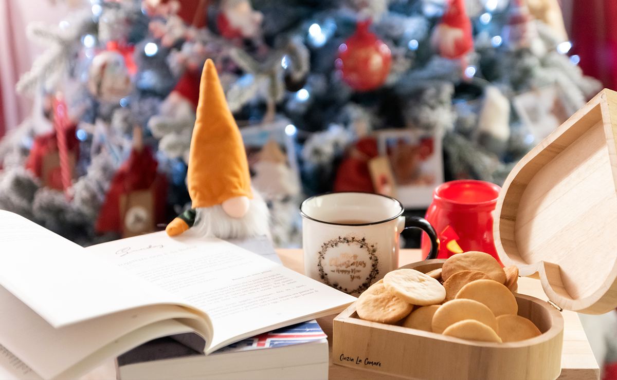 Piparkökur, biscotti islandesi in scatola di legno accanto a una tazza da tè con un albero di natale sullo sfondo