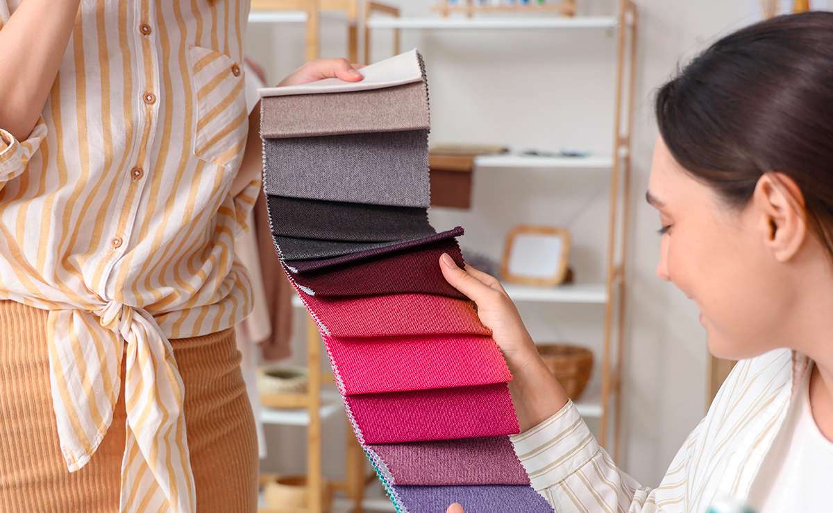 Donna osserva una selezione di tessuti in diverse sfumature durante un’analisi dei sottogruppi dell’armocromia per individuare la stagione cromatica personale.