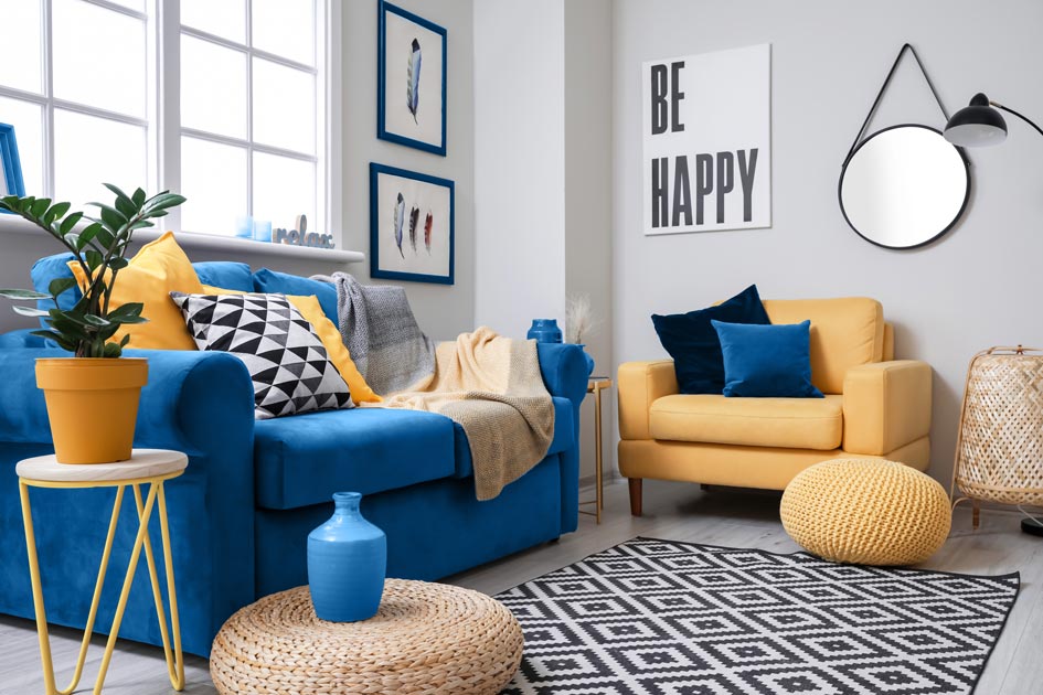 Soggiorno moderno con divani blu e giallo senape, decorato con cuscini geometrici