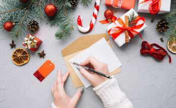 Mani femminili scrivono un biglietto di auguri su una cartolina natalizia