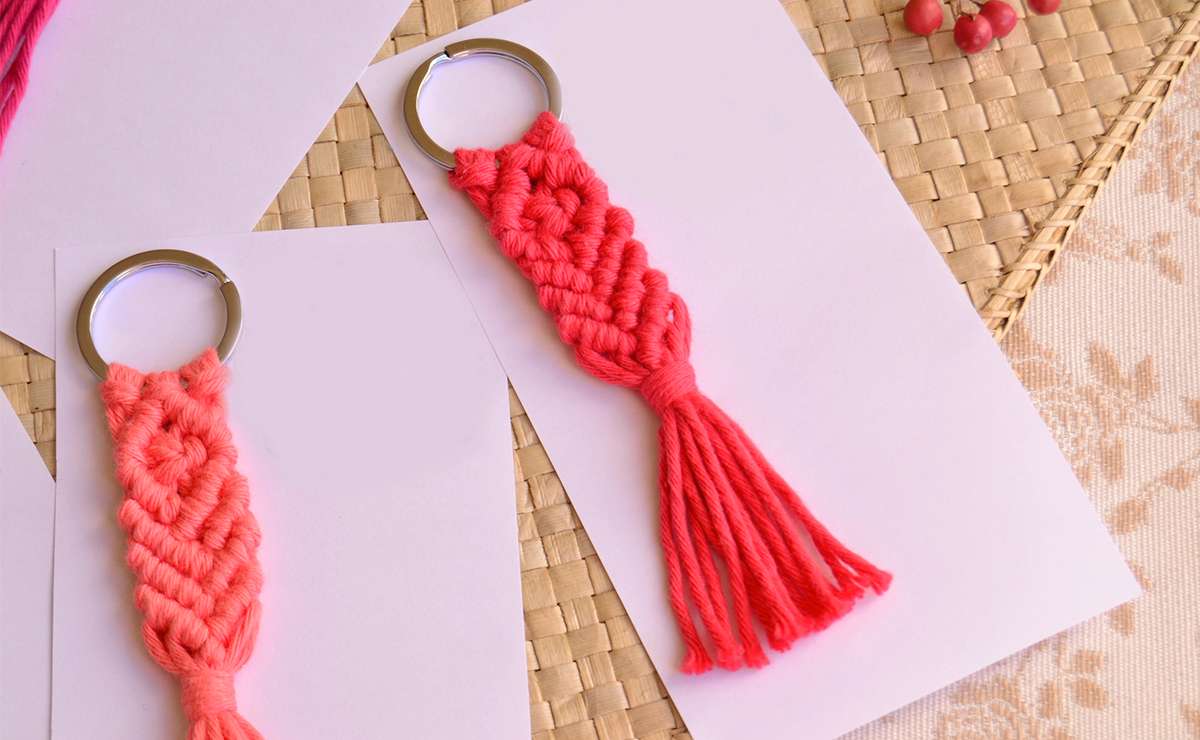 Bomboniere solidali per ospedali pediatrici: portachiavi fatti a mano in macramè rosso con anelli metallici, disposti su cartoncini bianchi.