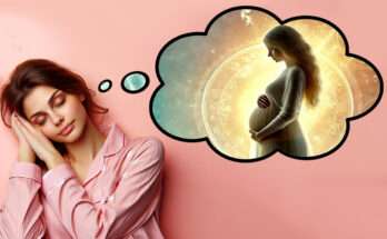 Una donna addormentata con un'espressione serena indossa un pigiama rosa. Sopra di lei appare un'illustrazione onirica all'interno di una nuvola di pensiero, che raffigura una figura femminile incinta circondata da luce dorata, simbolo di sogno e gravidanza.