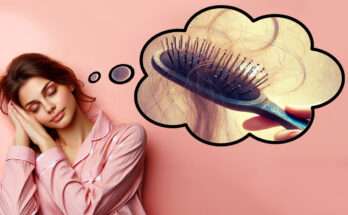 Una donna addormentata con un'espressione serena indossa un pigiama rosa. Sopra di lei, in una nuvola di pensiero, appare l'immagine onirica di una mano che regge una spazzola con capelli incastrati tra le setole, simbolo del sogno di perdere i capelli.