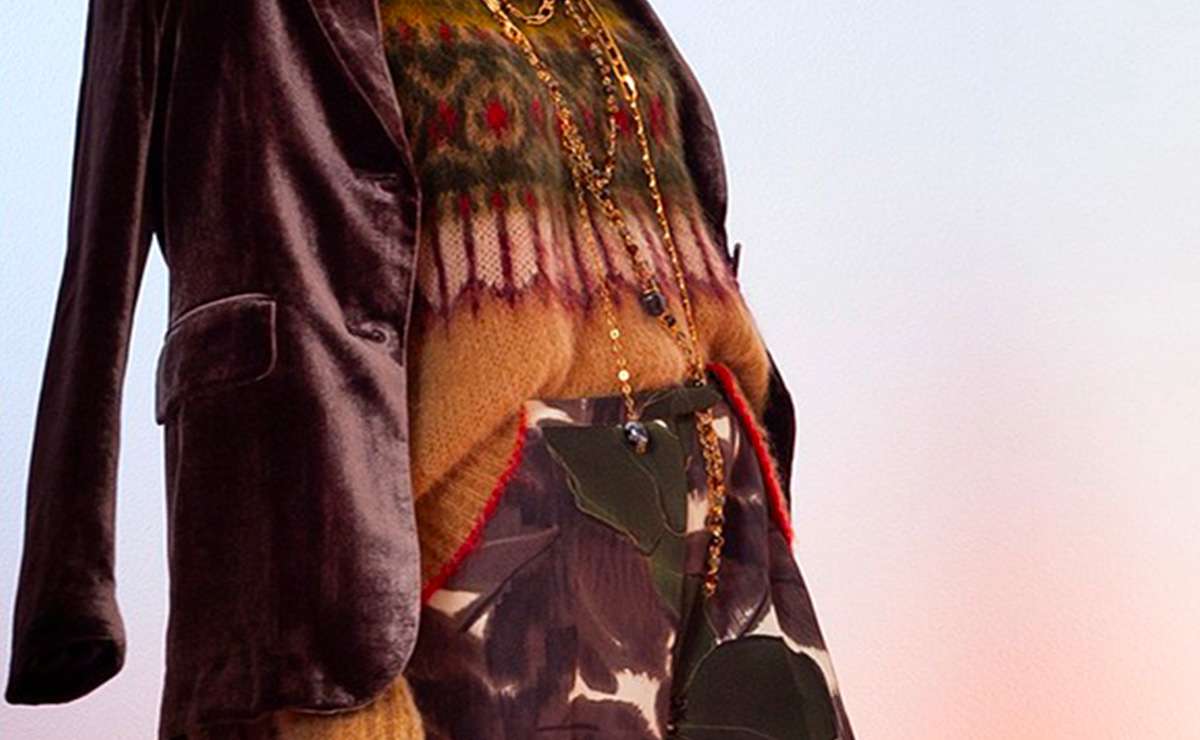 Outfit elegante con blazer in velluto, maglione a fantasia, collana dorata e pantaloni stampati, ideale per un look da ufficio sofisticato e originale.