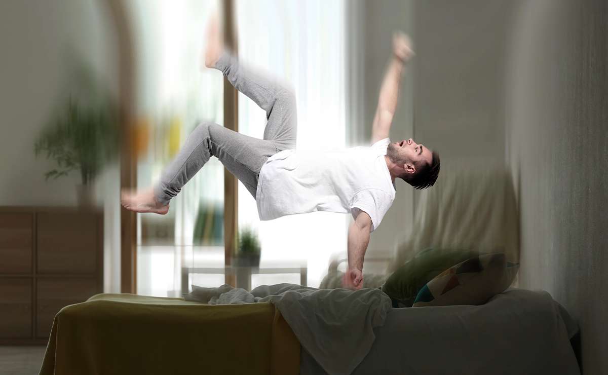 Uomo che sobbalza nel sonno sopra un letto sfatto, con un effetto visivo che simula la sensazione di cadere nel vuoto prima di addormentarsi.
