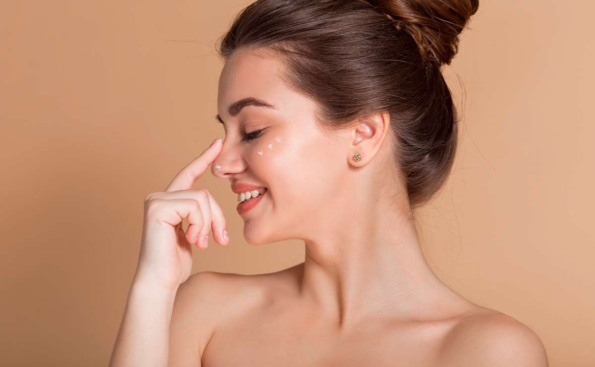 Donna con base trucco estiva leggera applica crema sul viso per ottenere un make-up naturale, fresco e luminoso