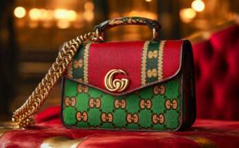 Borsa Gucci con design rosso e verde, dettagli in oro e logo GG, posata su un elegante divano rosso con sfondo illuminato.