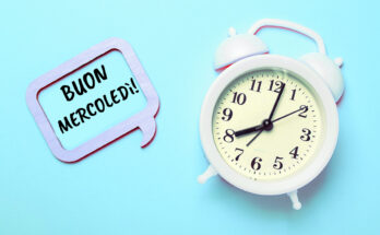 Sveglia bianca su sfondo azzurro con fumetto in legno e scritta “Buon mercoledì!”: immagine allegra e motivazionale per augurare buon mercoledì.