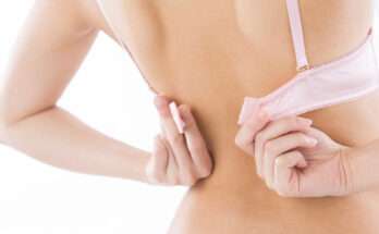 Donna di schiena che si sfila un reggiseno rosa