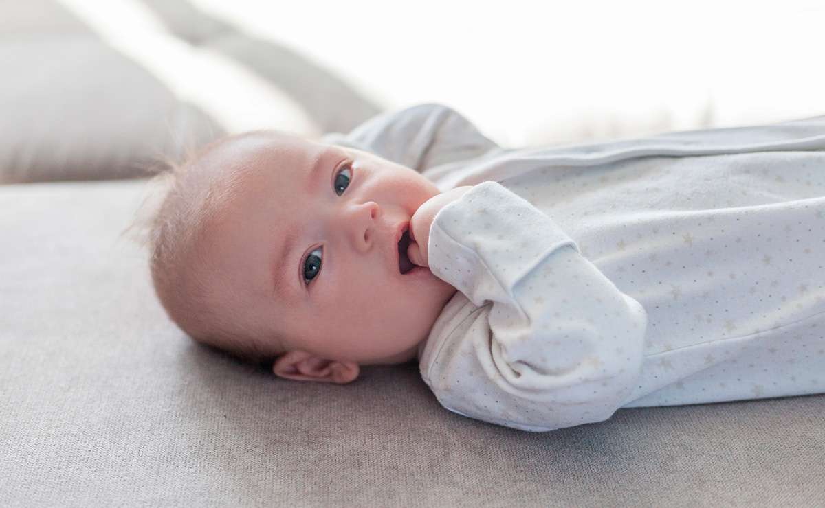 Neonato con pigiamino bianco a stelline sdraiato su un divano
