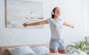 Persona che si risveglia con serenità ascoltando musica in cuffia, in una stanza luminosa: immagine legata alla pratica della mindfulness mattutina.