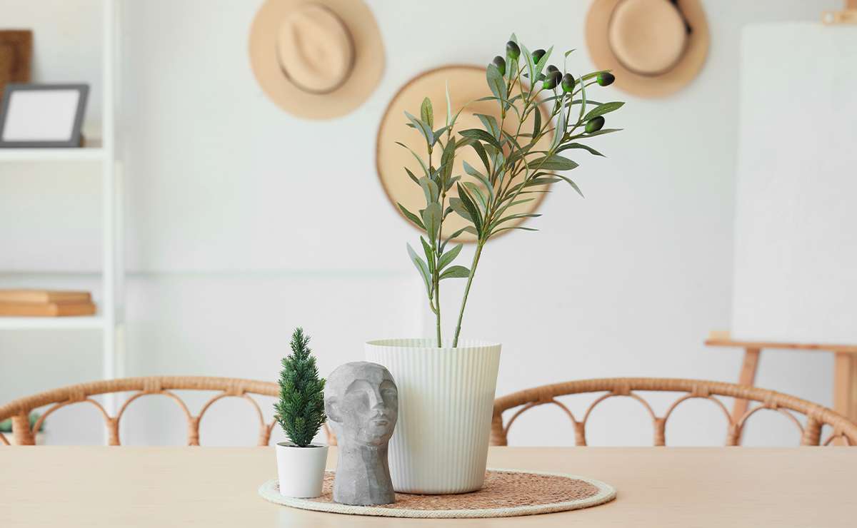 Decorazione da tavolo in stile Feng Shui con piante verdi, busto in pietra e sedie in rattan in un appartamento moderno e luminoso