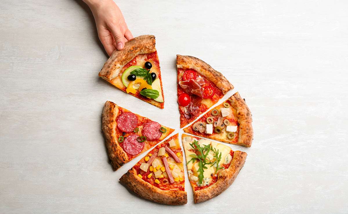 Fetta di pizza in mano scelta tra sei spicchi con condimenti diversi, tra cui ananas, salame, verdure, olive e prosciutto: esempi di pizze insolite nel mondo.