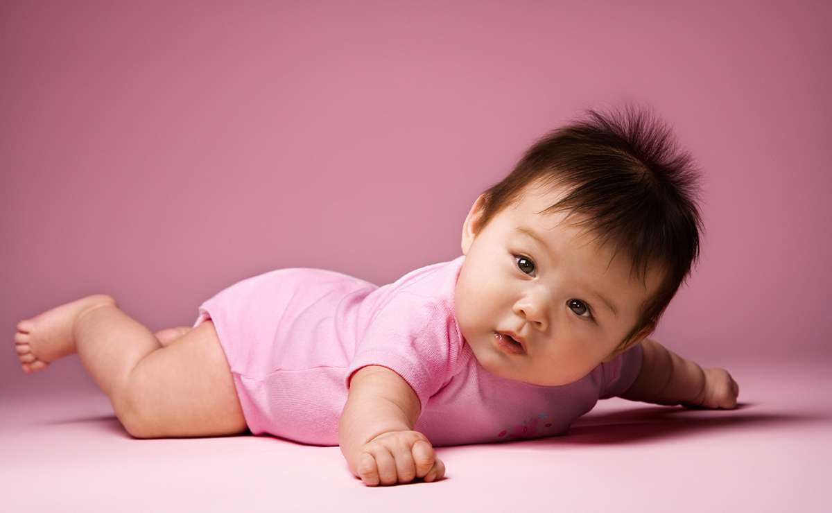 Bambina sdraiata su sfondo rosa, con body rosa e capelli scuri, simbolo della dolcezza legata ai nomi femminili con la G.