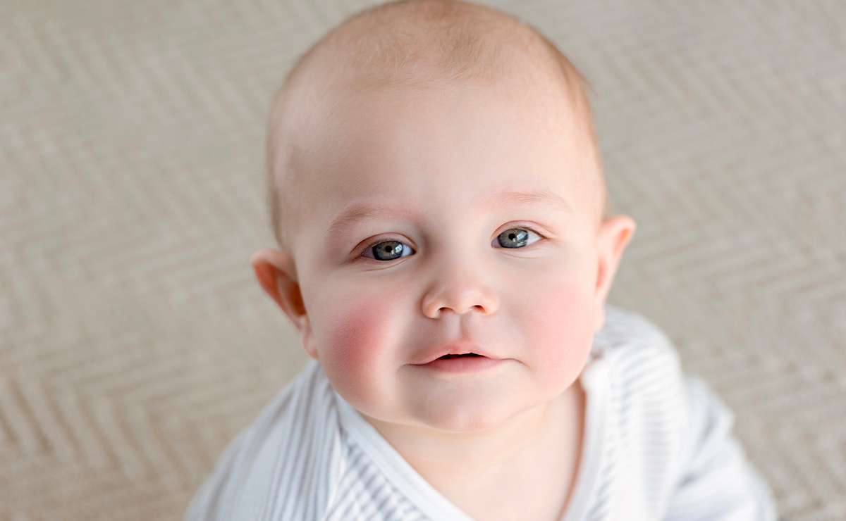Primo piano di un neonato con occhi chiari e guance arrossate