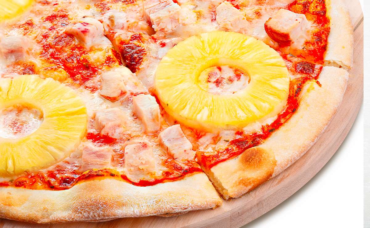 Pizza hawaiana con ananas a fette e cubetti di prosciutto su base di mozzarella e pomodoro, esempio controverso di pizza all’estero.