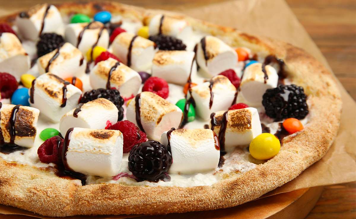 Pizza dessert con marshmallow, frutti di bosco, caramelle colorate e salsa al cioccolato: esempio di pizza dolce estrema diffusa all’estero.