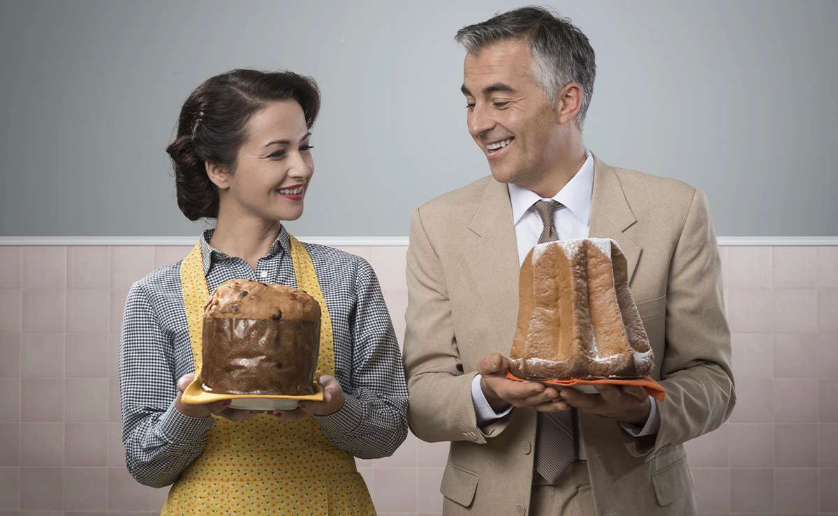 Coppia elegante con panettone e pandoro in mano, sorridenti in cucina anni ’50: confronto tra i due dolci natalizi tradizionali italiani.