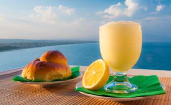 Granita siciliana al limone con brioscia col tuppo servita vista mare, tipica colazione estiva siciliana.