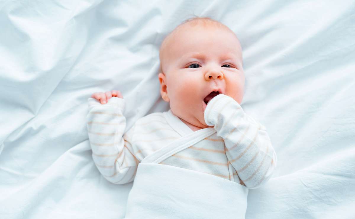 Neonato sdraiato con pigiamino chiaro