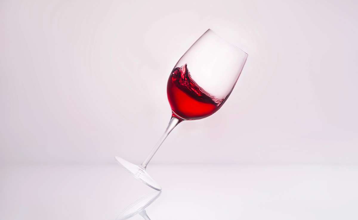 Calice di vino rosso in equilibrio su sfondo chiaro