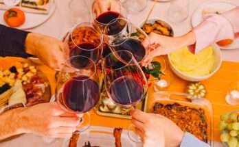 Brindisi con calici di vino rosso attorno a una tavola imbandita per il pranzo