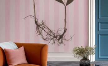 Angolo lettura moderno con poltrona color ruggine e parete decorata da carta da parati rosa a righe con motivo botanico