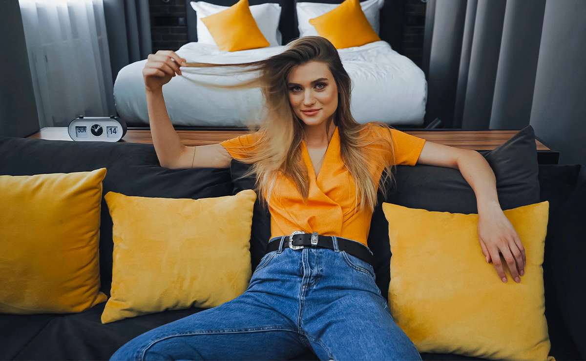 Ragazza seduta su un divano con cuscini gialli coordinati alla maglietta
