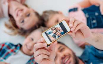 Famiglia sdraiata insieme mentre scatta un selfie con lo smartphone