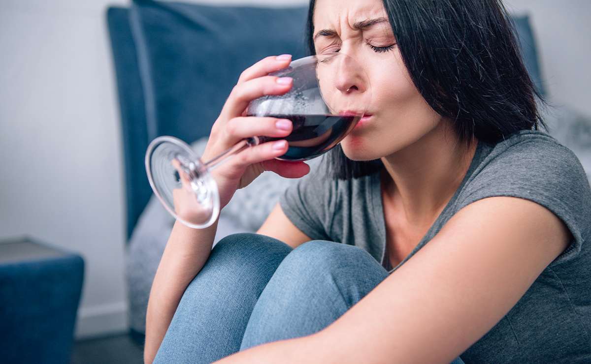 Donna seduta con un bicchiere di vino rosso tra le mani