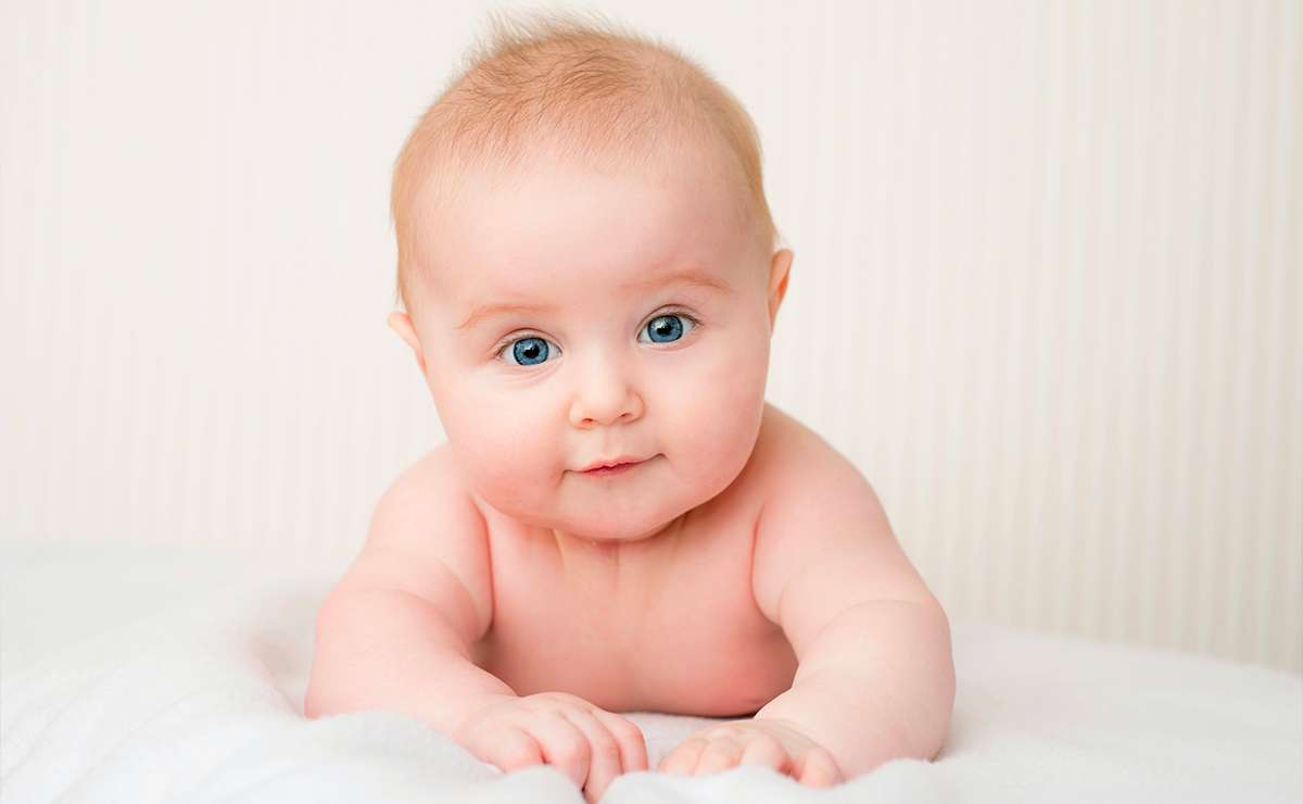 Neonato con occhi azzurri disteso su una coperta bianca