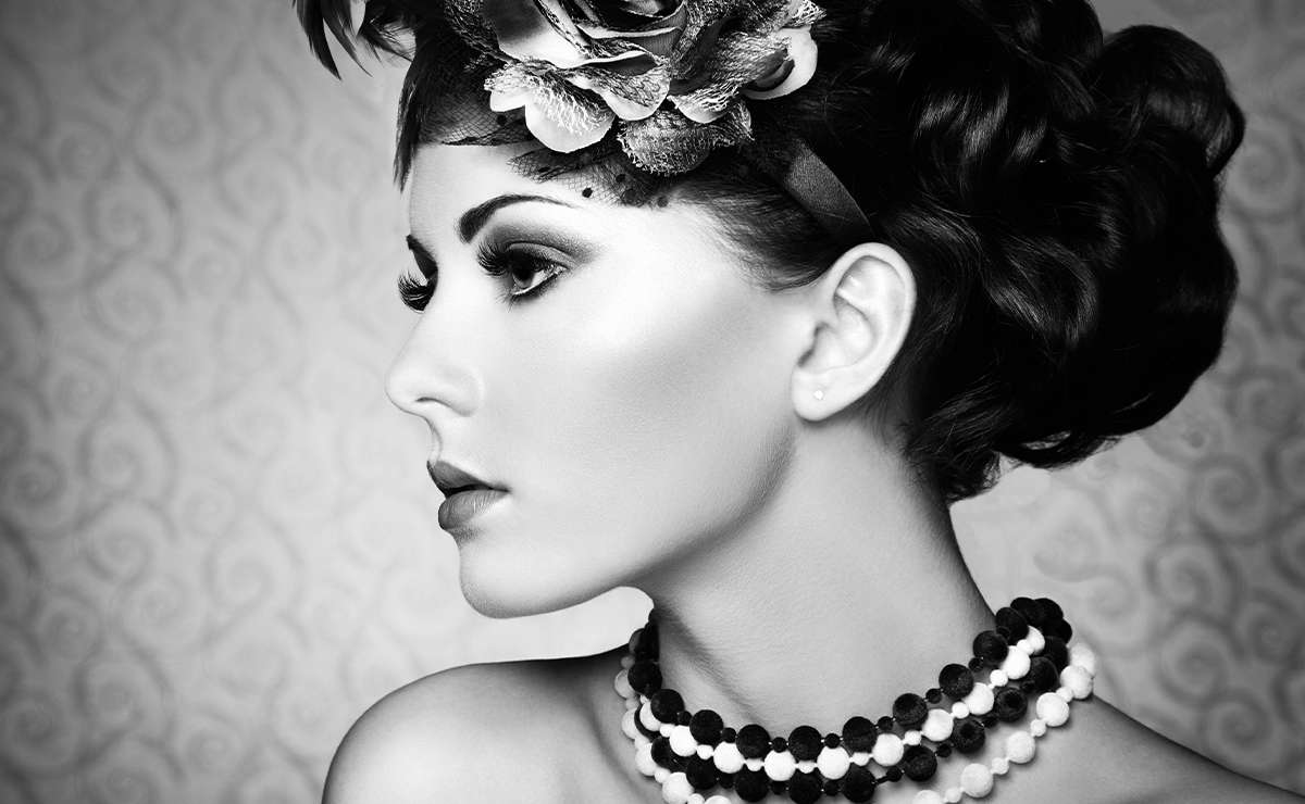 Donna elegante in stile anni ’30 con acconciatura ondulata e collana di perle