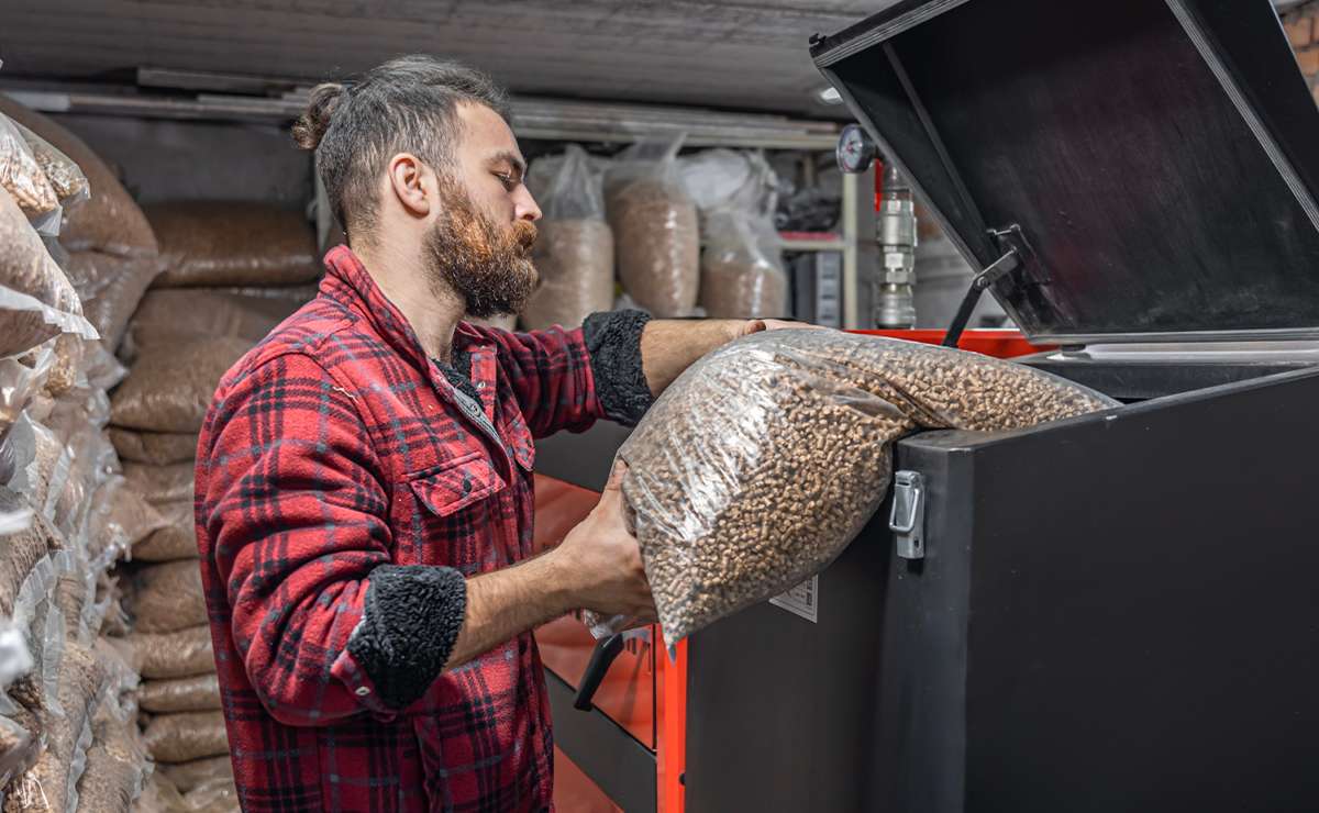 Uomo che versa pellet in una caldaia a biomassa