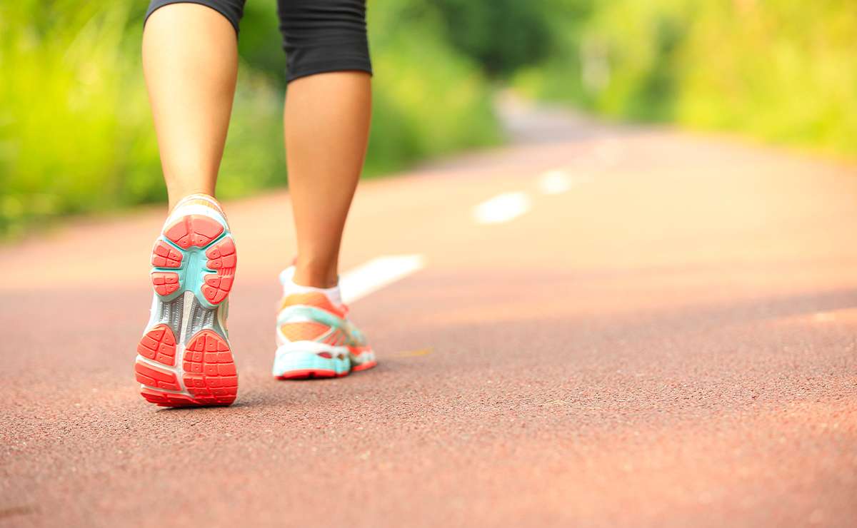 Persona che cammina su una strada immersa nel verde indossando scarpe da ginnastica colorate