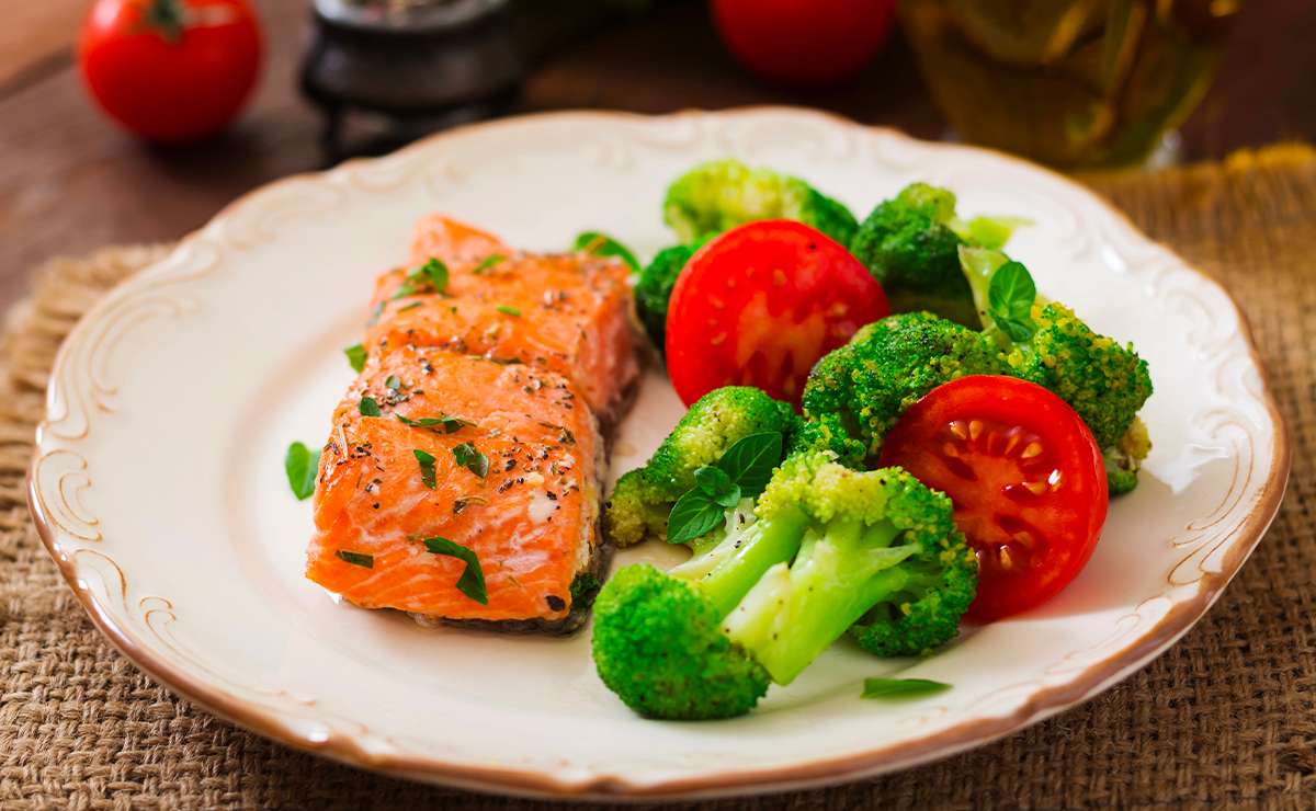 Salmone al forno servito con broccoli e pomodorini freschi in un piatto
