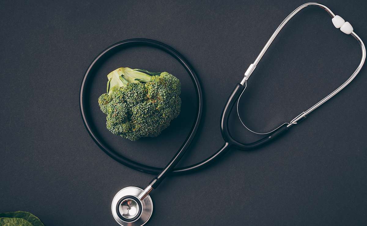 Broccolo appoggiato al centro di uno stetoscopio su sfondo scuro