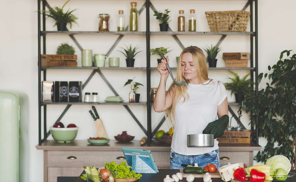 Donna che assaggia una pietanza mentre cucina in una cucina moderna