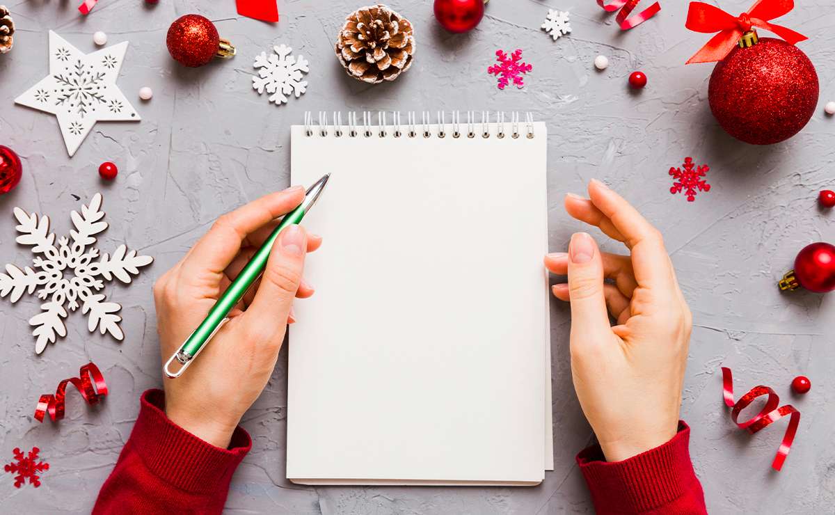 Mani che tengono un taccuino vuoto circondato da decorazioni natalizie