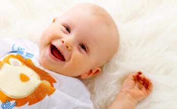 Neonato sorridente sdraiato su una coperta bianca