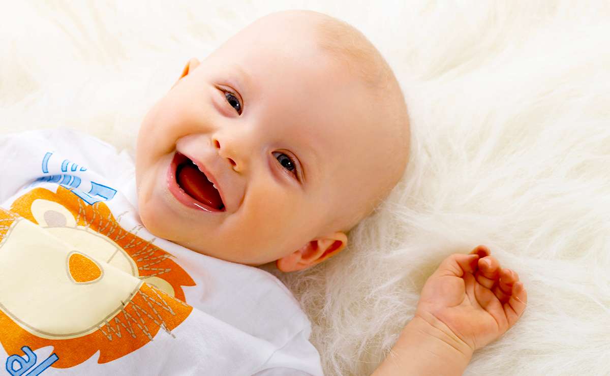 Neonato sorridente sdraiato su una coperta bianca