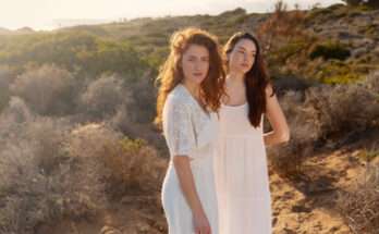 Due donne in abiti bianchi immersi nella natura al tramonto