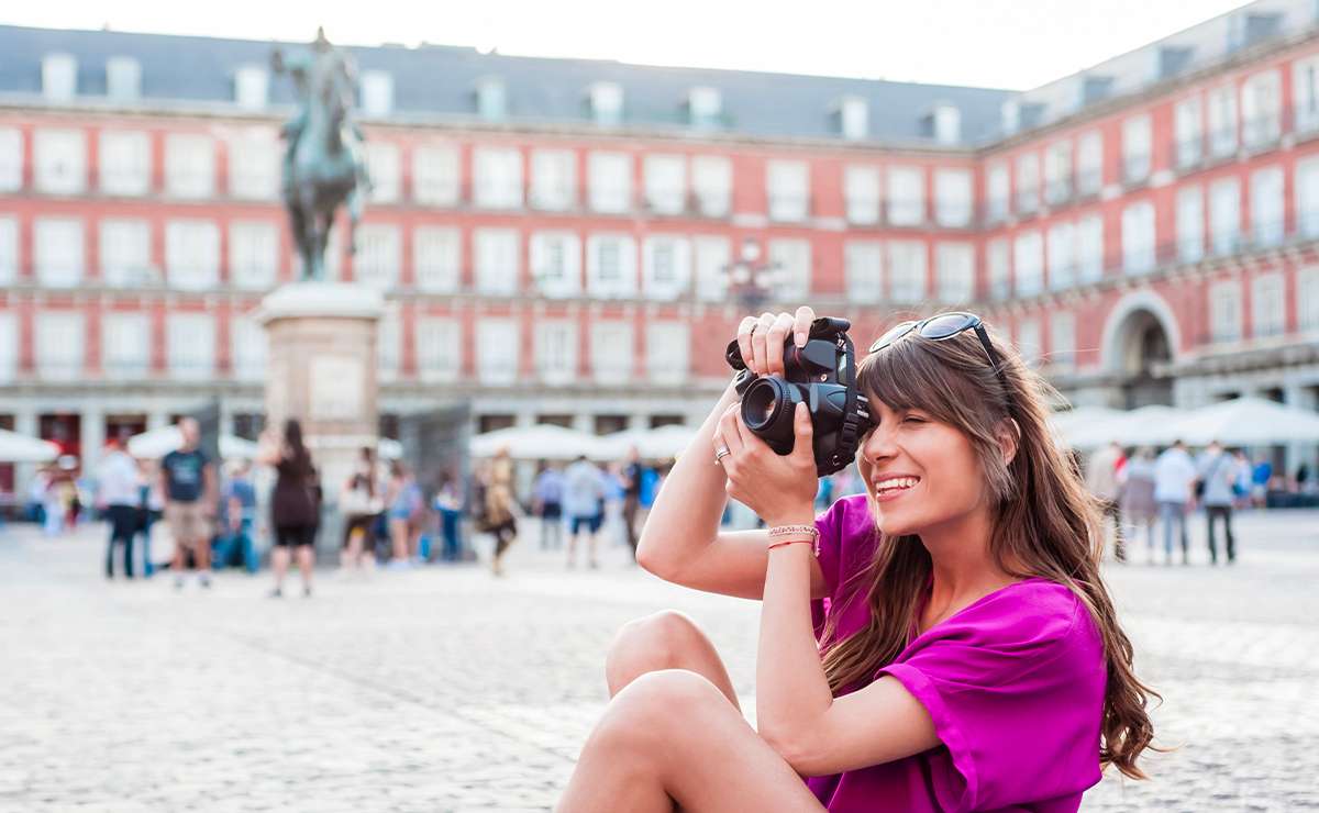 Ragazza che fotografa seduta in Plaza Mayor a Madrid