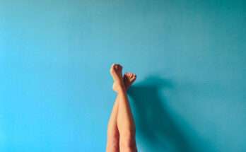 Gambe depilate sollevate contro una parete azzurra