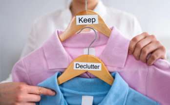Persona che tiene due grucce con maglie colorate, una etichettata “Keep” e una “Declutter”