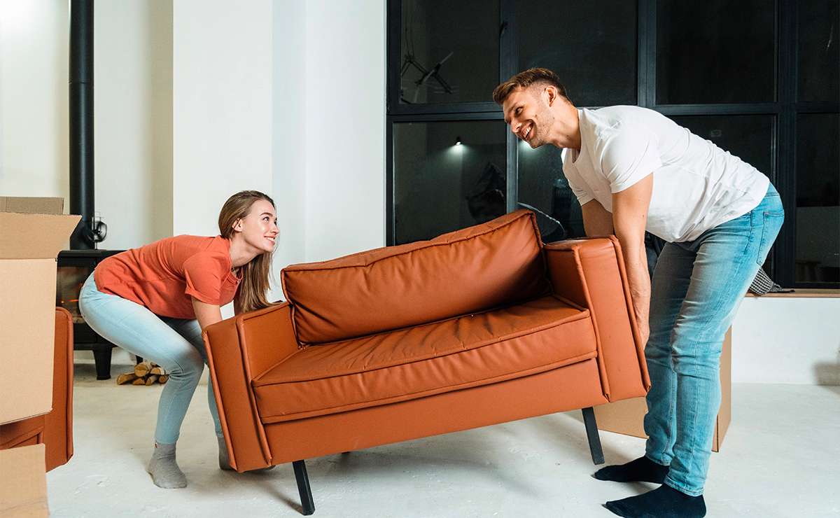Coppia che sposta un divano moderno color terracotta