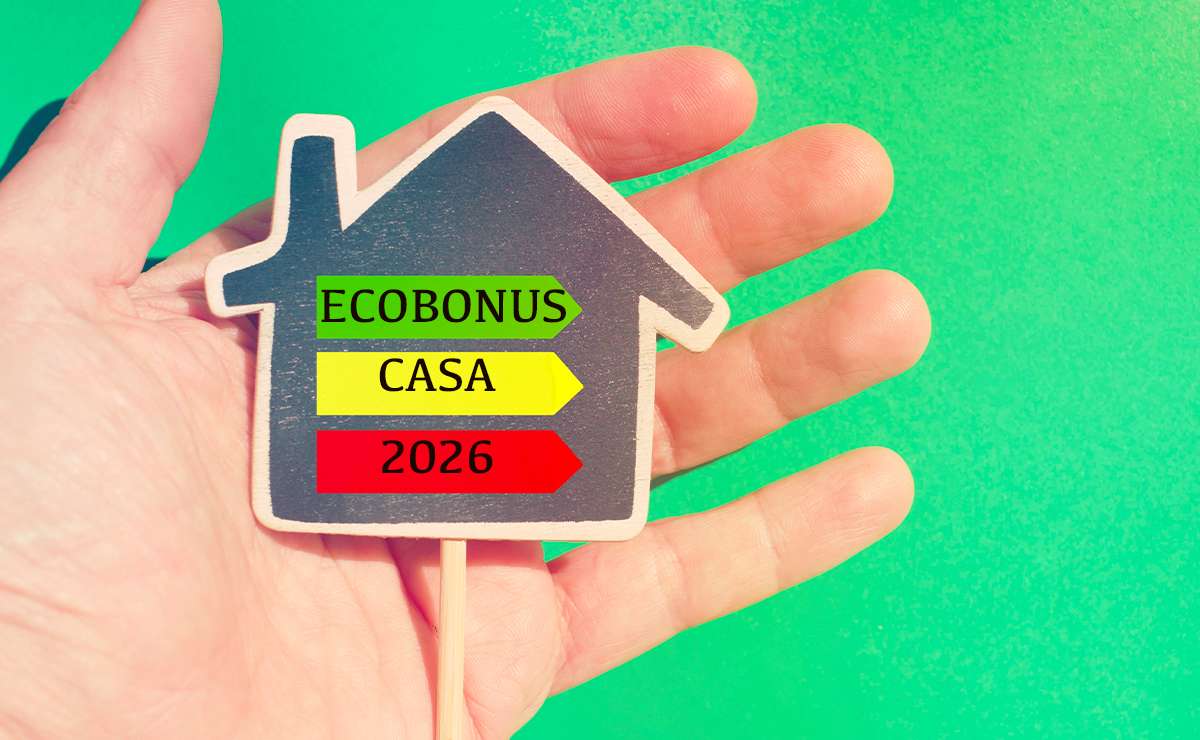 Mano che regge un cartoncino a forma di casa con la scritta “Ecobonus casa 2026”,