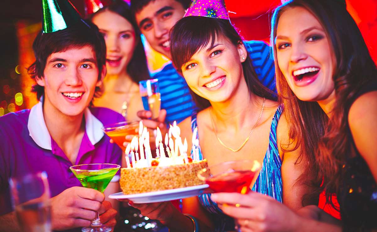 Ragazzi che festeggiano un diciottesimo compleanno con torta accesa da candeline