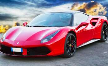 Ferrari 488 rossa con tetto nero parcheggiata all’aperto al tramonto